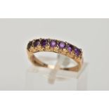 A 9CT GOLD AMETHYST HALF ETERNITY RING, designed with a row of seven circular cut amethysts,