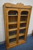 A PINE GLAZED TWO DOOR BOOKCASE, with four fixed shelves, width 96cm x depth 34cm x height 169cm