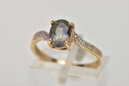 A 9CT GOLD TOPAZ AND DIAMOND DRESS RING, designed with a four claw set, oval cut topaz (mystic