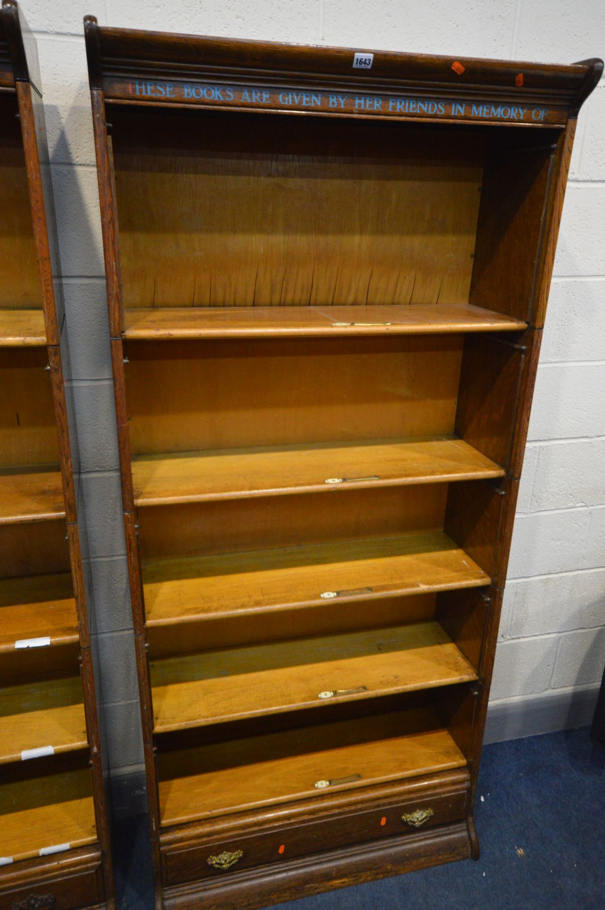 AN OAK FIVE SECTION BOOKCASE, with stencilled writing to top frieze, the bottom section with a