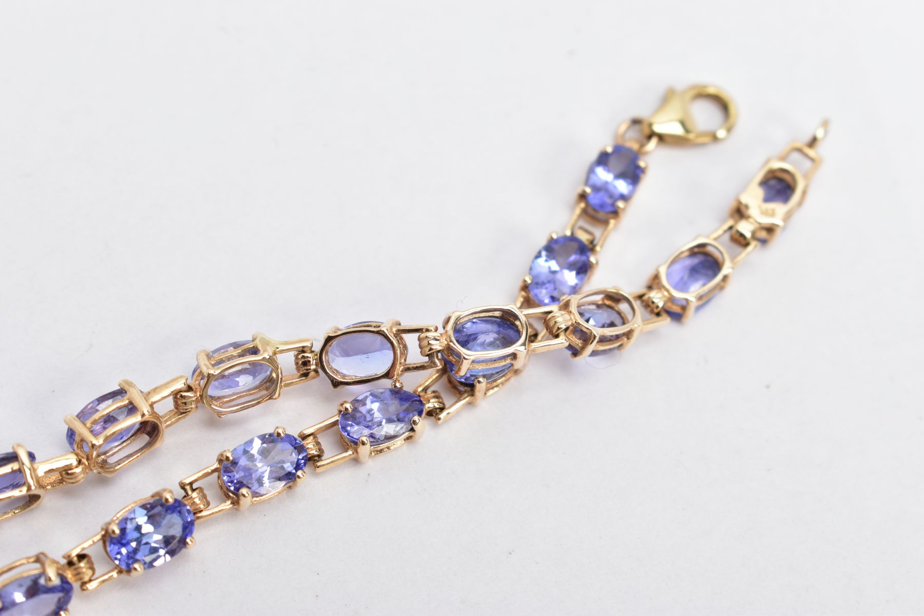 A 9CT GOLD TANZANITE LINE BRACELET, designed with a row of oval cut tanzanite's, fitted with a - Image 3 of 3