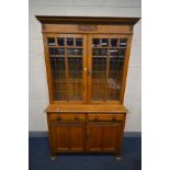 AN EARLY 20TH CENTURY ARTS AND CRAFTS OAK TWO DOOR LEAD GLAZED BOOKCASE, with two drawers, over