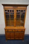 AN EARLY 20TH CENTURY ARTS AND CRAFTS OAK TWO DOOR LEAD GLAZED BOOKCASE, with two drawers, over