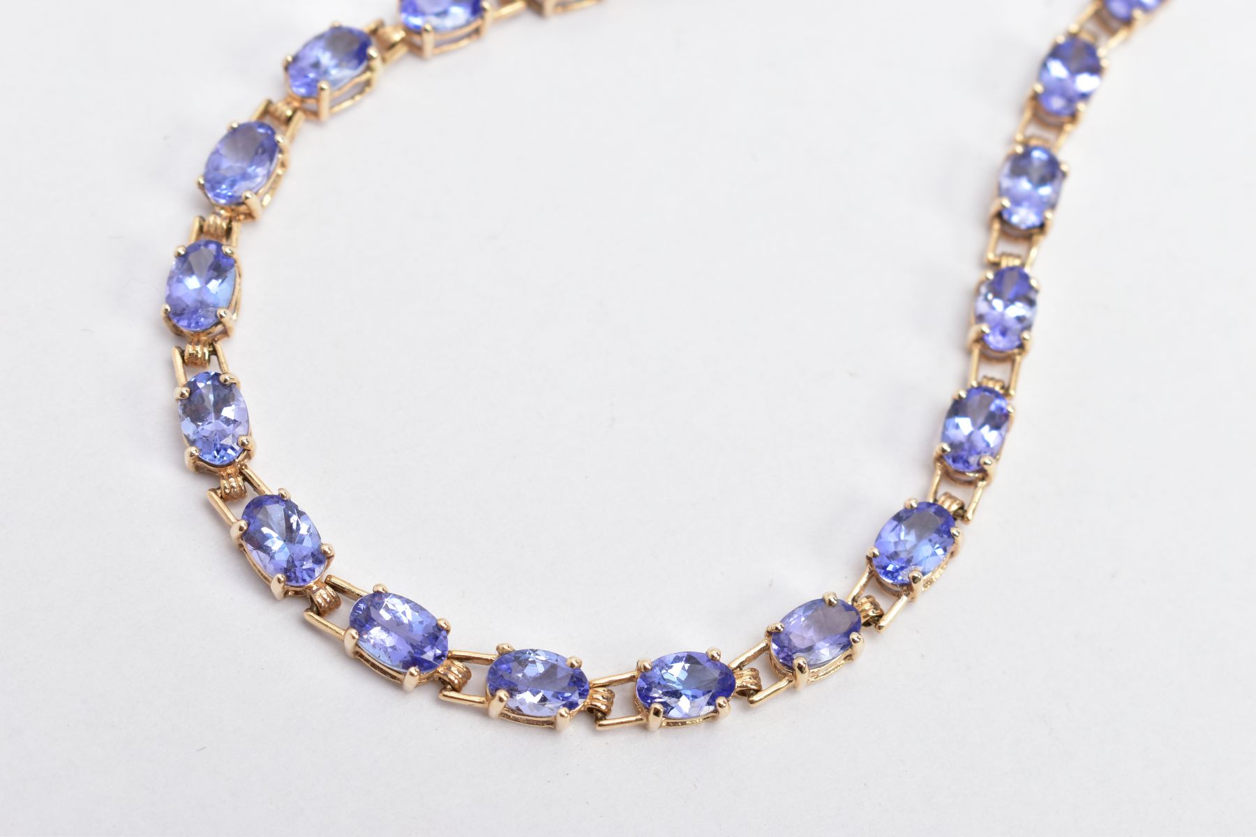 A 9CT GOLD TANZANITE LINE BRACELET, designed with a row of oval cut tanzanite's, fitted with a - Image 2 of 3