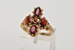 A 9CT GOLD GARNET RING, in the form of a cross, set with four oval cut garnets, each within an