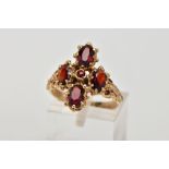 A 9CT GOLD GARNET RING, in the form of a cross, set with four oval cut garnets, each within an