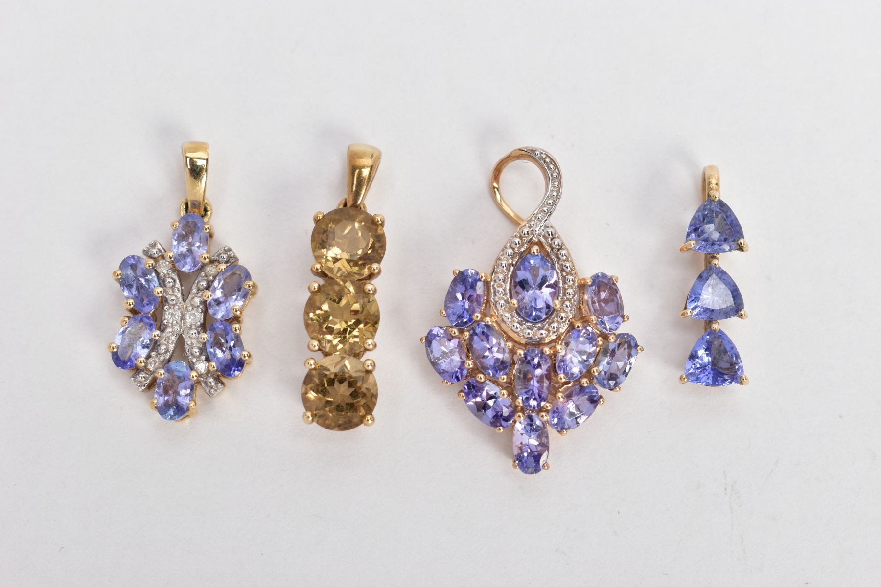 FOUR YELLOW METAL GEM SET PENDANTS, the first set with three circular cut citrines, tapered bail,