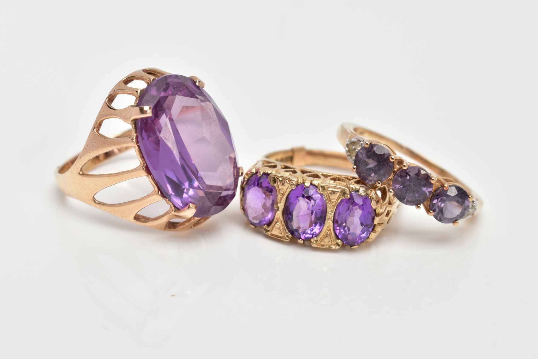 THREE 9CT GOLD AMETHYST DRESS RINGS, a large oval cut amethyst, ring size O, a three stone - Image 2 of 3