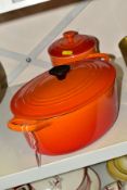 A LE CREUSET ORANGE ENAMELLED OVAL CAST IRON CASSEROLE POT AND COVER, oval 25cm, signs of light use,