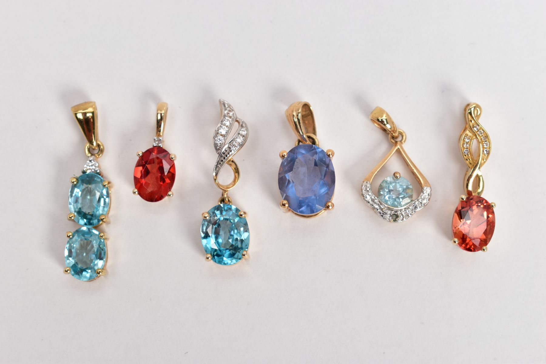 FIVE GEM SET YELLOW METAL PENDANTS, the first set with two oval cut blue topaz, fitted with a