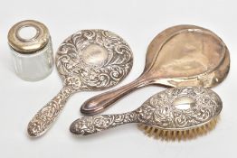 FOUR SILVER VANITY PIECES, to include an embossed foliate and scroll detailed mirror with a vacant