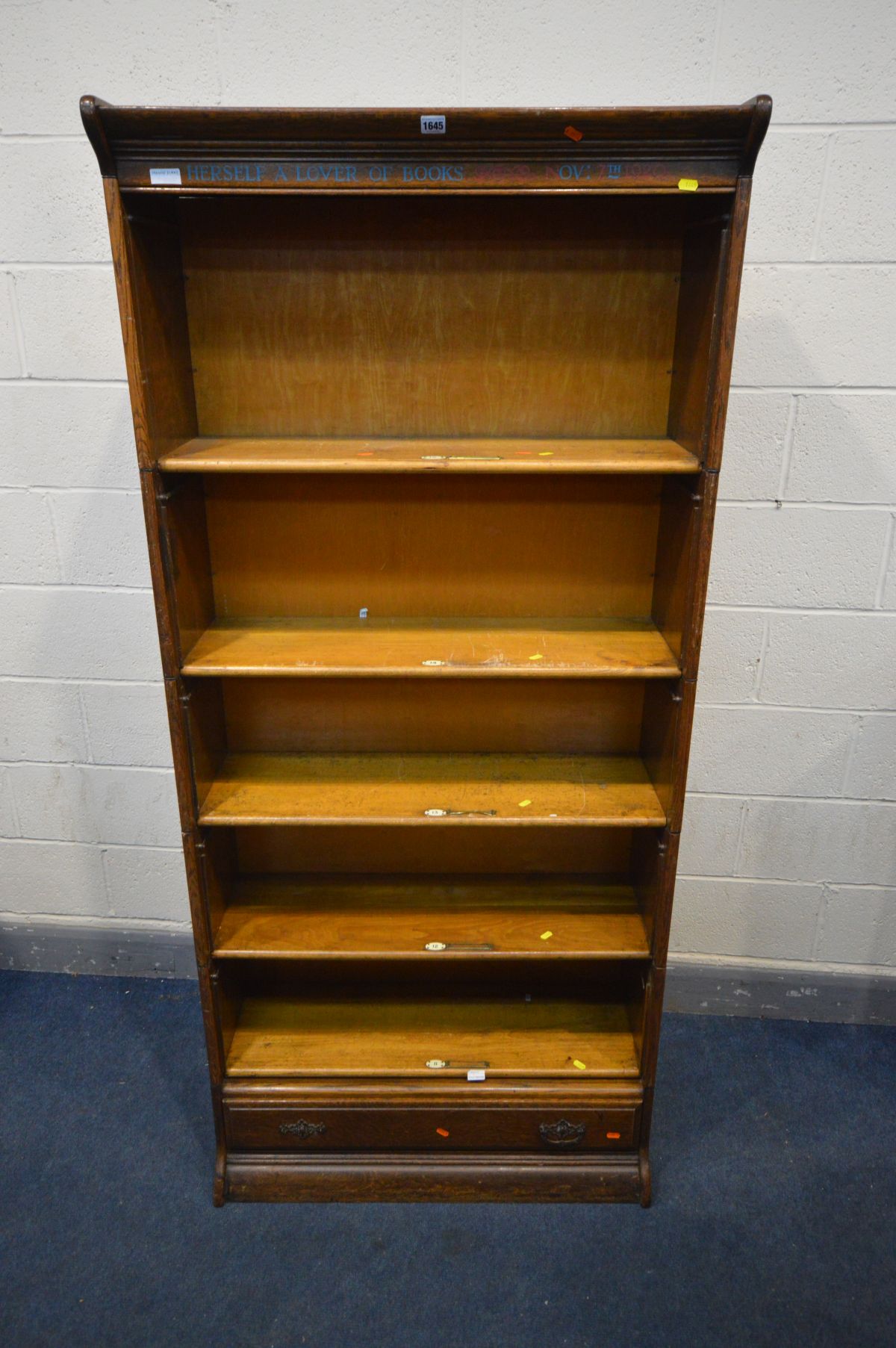 AN OAK FIVE SECTION BOOKCASE, with stencilled writing to top frieze, the bottom section with a