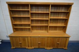 A LARGE LIMED OAK BOOKCASE, the three division top section with twelve adjustable shelves, above