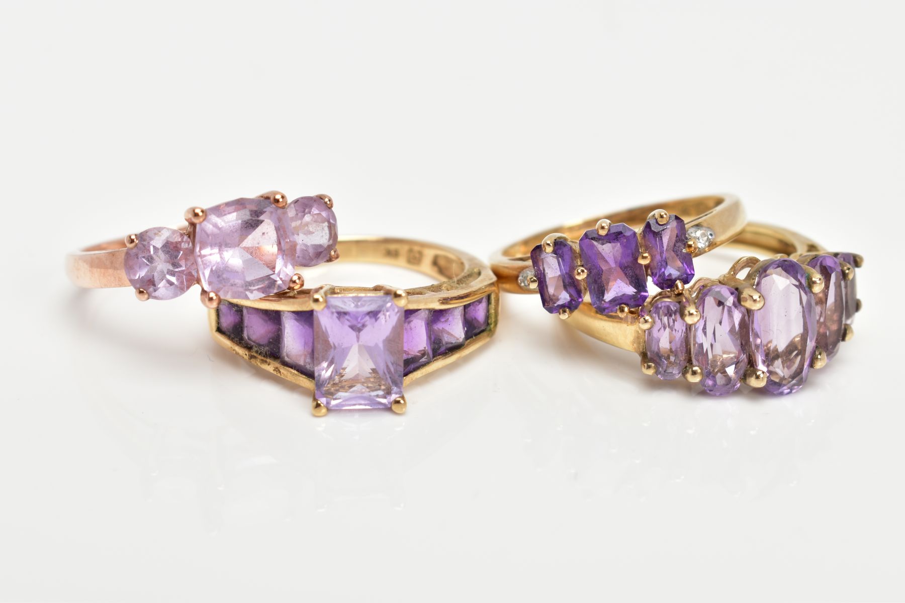 FOUR 9CT GOLD AMETHYST DRESS RINGS, three yellow gold and one rose gold, each set with vary cut