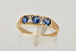 A YELLOW METAL SAPPHIRE AND DIAMOND RING, designed with a row of three circular cut blue