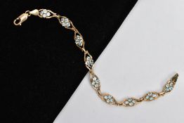 A 9CT GOLD TOPAZ LINE BRACELET, designed with nine openwork links, each set with four circular cut