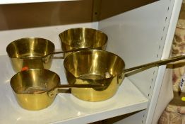 A SET OF FOUR GRADUATED BRASS SAUCEPANS, one lacking the handle, all with pouring lips, sizes from