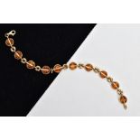 A 9CT GOLD AMBER SET LINE BRACELET, designed with ten circular cut amber set links, interspaced with