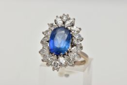 AN 18CT WHITE GOLD SAPPHIRE AND DIAMOND CLUSTER RING, the oval sapphire within a twelve claw