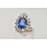 AN 18CT WHITE GOLD SAPPHIRE AND DIAMOND CLUSTER RING, the oval sapphire within a twelve claw