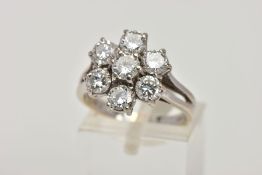 AN 18T WHITE GOLD SEVEN STONE DIAMOND CLUSTER RING, designed as seven claw set brilliant cut