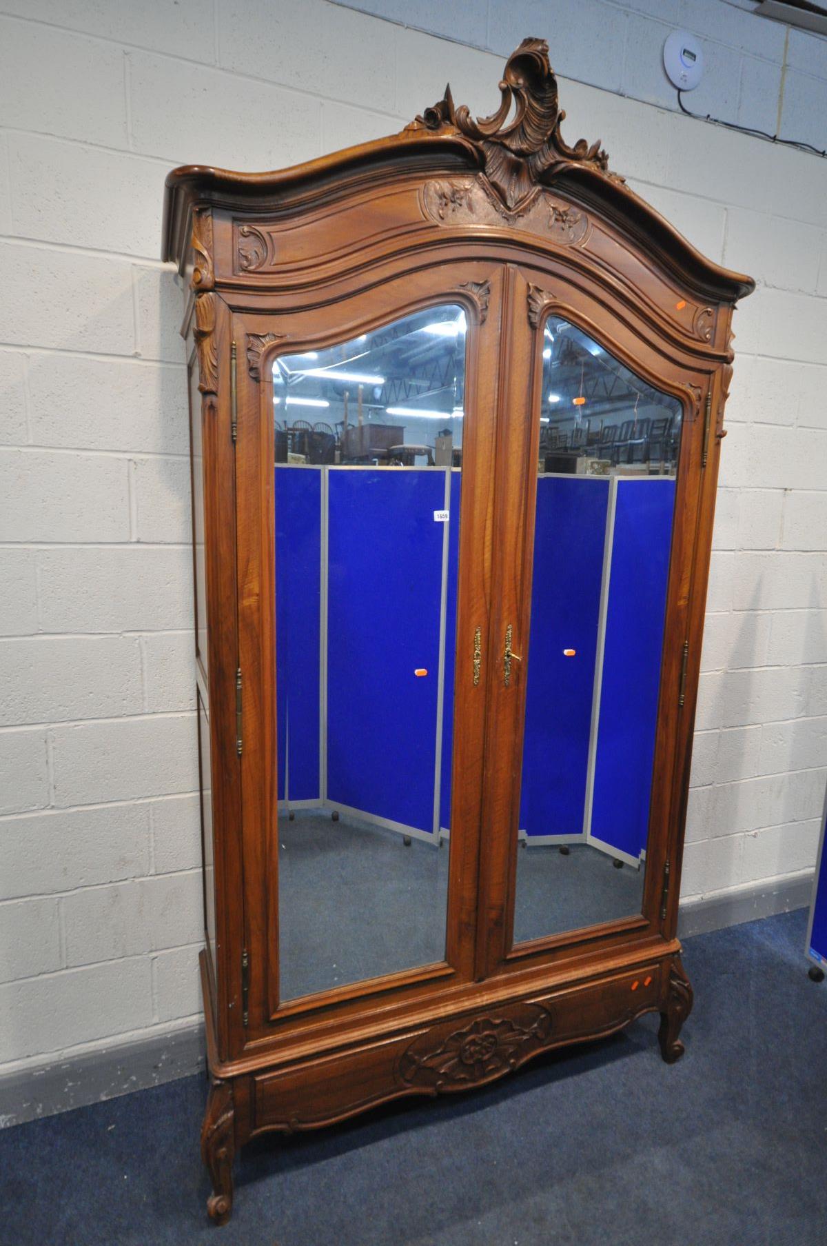 A FRENCH HARDWOOD ARMOIRE, with double bevelled edge mirror doors, enclosing three adjustable