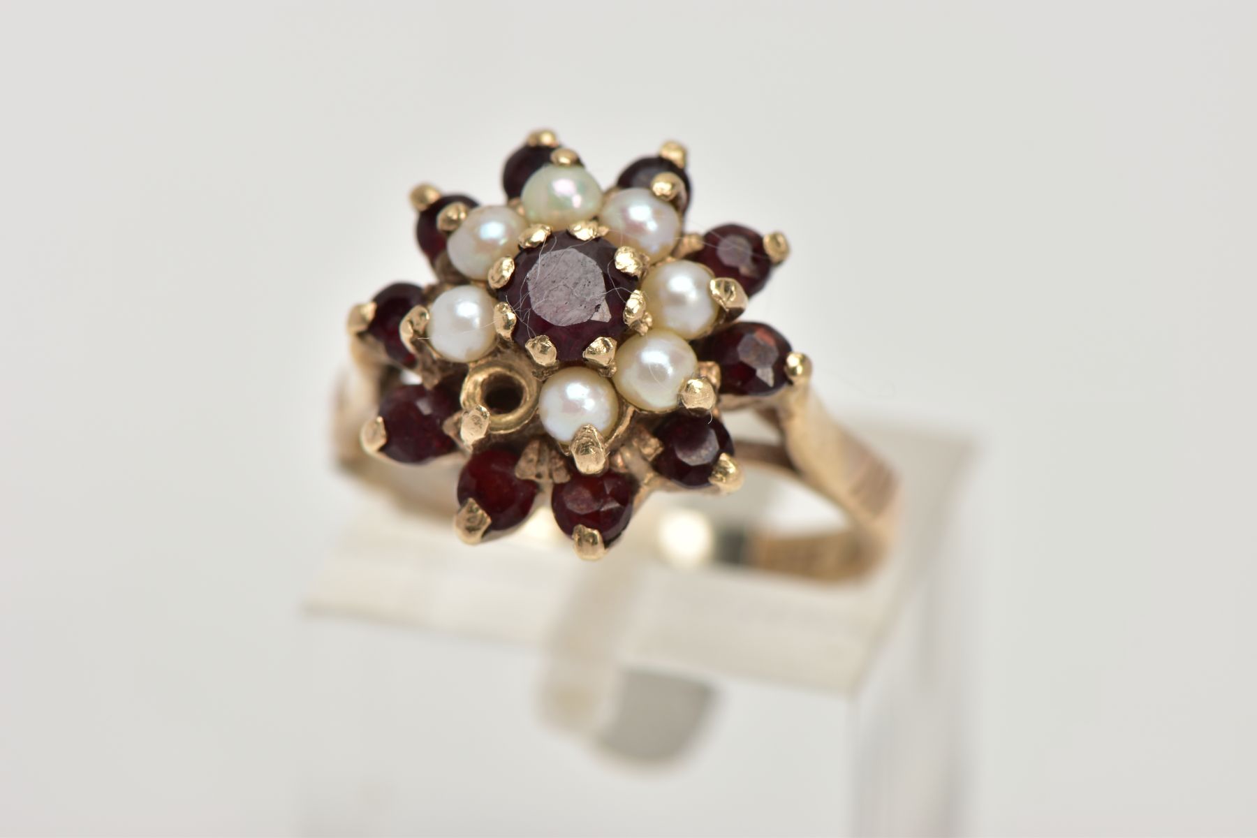 A GEM CLUSTER RING, designed as a tiered cluster of claw set red gems assessed as garnets and