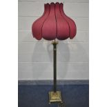 A BRASS CORINTHIAN COLUMN STANDARD LAMP, on claw feet, with a red tulip shaped shade, height to