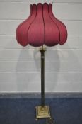 A BRASS CORINTHIAN COLUMN STANDARD LAMP, on claw feet, with a red tulip shaped shade, height to