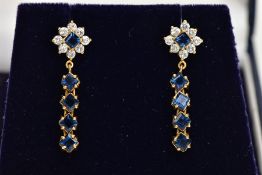 A PAIR OF YELLOW METAL DROP EARRINGS, each earring set with a square cut blue sapphire within a