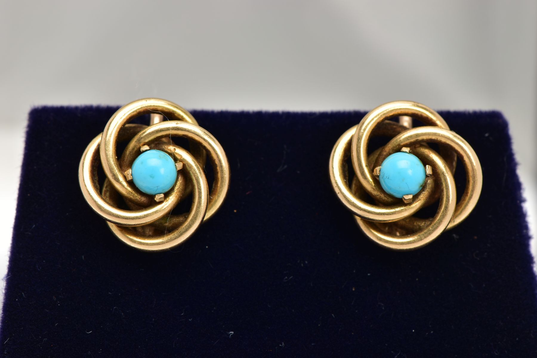 A PAIR OF EARRINGS, of interlocking circular design each set with a central turquoise cabochon, with