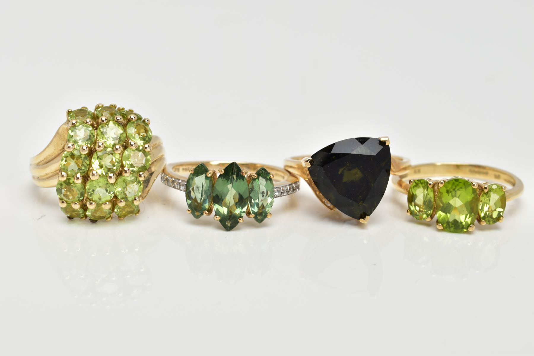 FOUR 9CT GOLD GEMSET RINGS, to include a three stone ring, oval cut peridot, prong set with