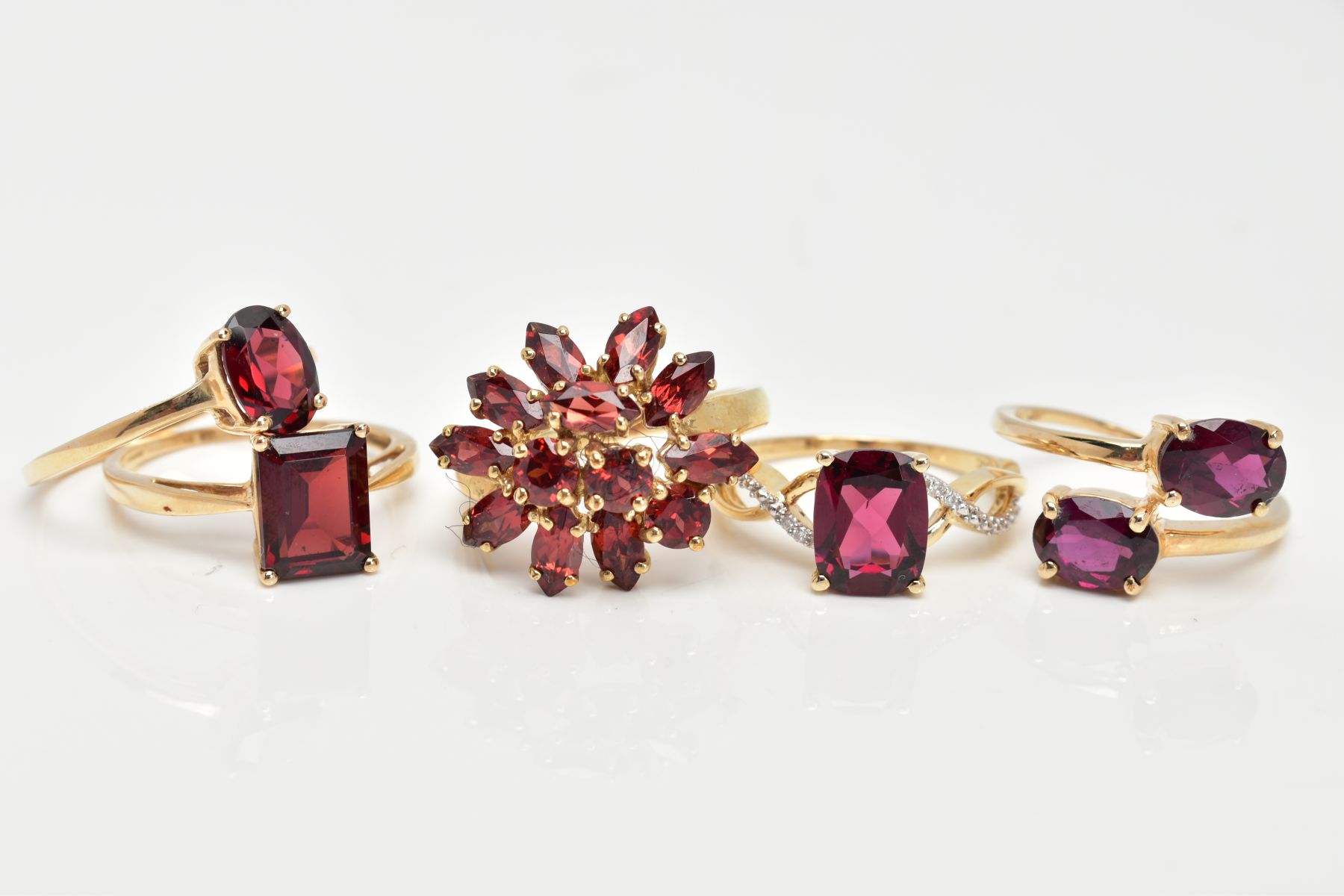 FIVE 9CT GOLD GEM SET DRESS RINGS, various designs, set with vary cut garnets, one also set with