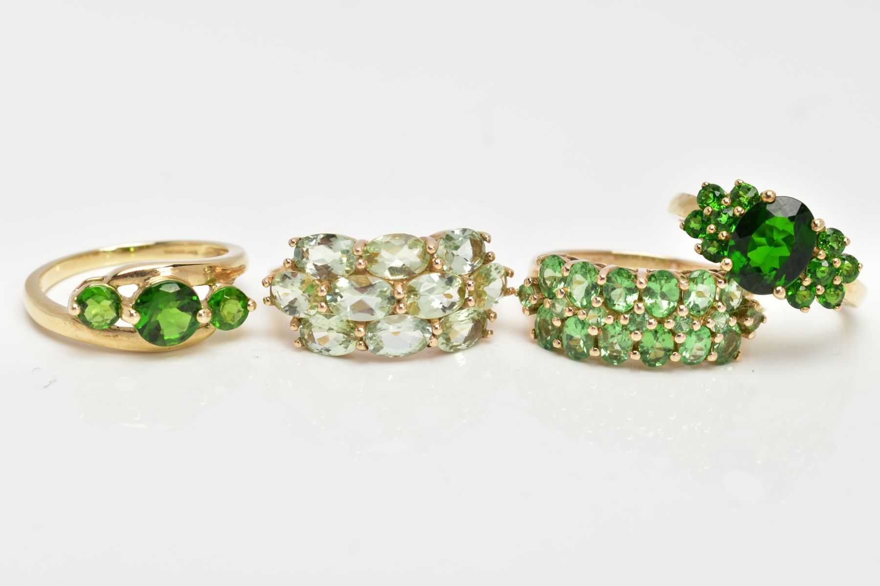 FOUR 9CT GOLD GEMSET RINGS, to include a three stone ring, assessed as circular cut diopside,