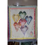 A PATCHWORK QUILT, with rod for hanging, backed in a floral print, featuring six different colour