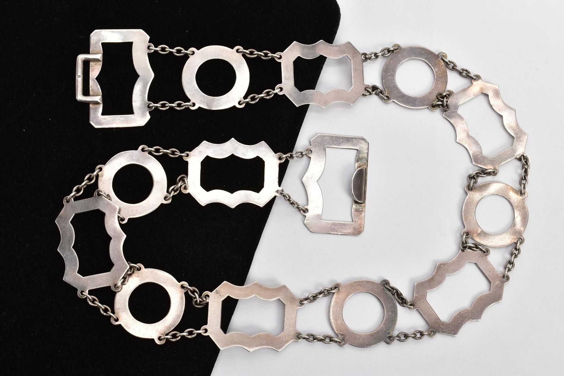 A SILVER OPENWORK BELT, designed with openwork circular and wavy links, each interspaced with curb