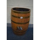 AN OAK OVAL COOPERED BARRELL with a brass banding and coat of arms printed to the front, height 61cm