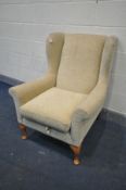 A GOLD UPHOLSTERED WING BACK ARMCHAIR, on beech legs