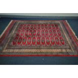 A 20TH CENTURY WOOLLEN GROUND RUG, of a geometric design, red field and multistrap border, 305cm x