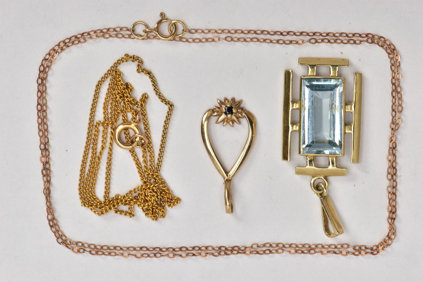 A 9CT GOLD TOPAZ PENDANT, TWO YELLOW METAL CHAINS AND A YELLOW METAL PENDANT, the first pendant of