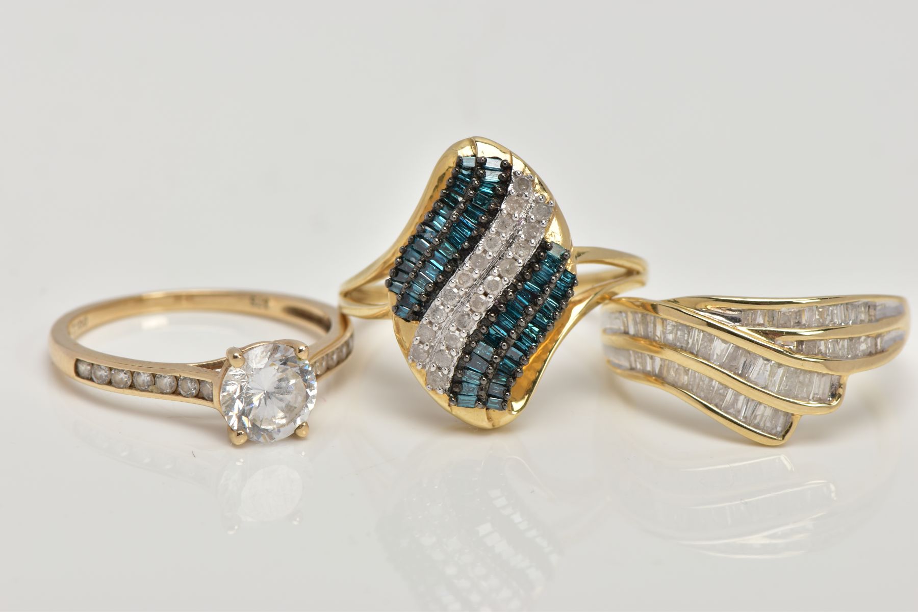THREE 9CT GOLD GEM SET RINGS, the first of cross over design set with baguette cut diamonds, total