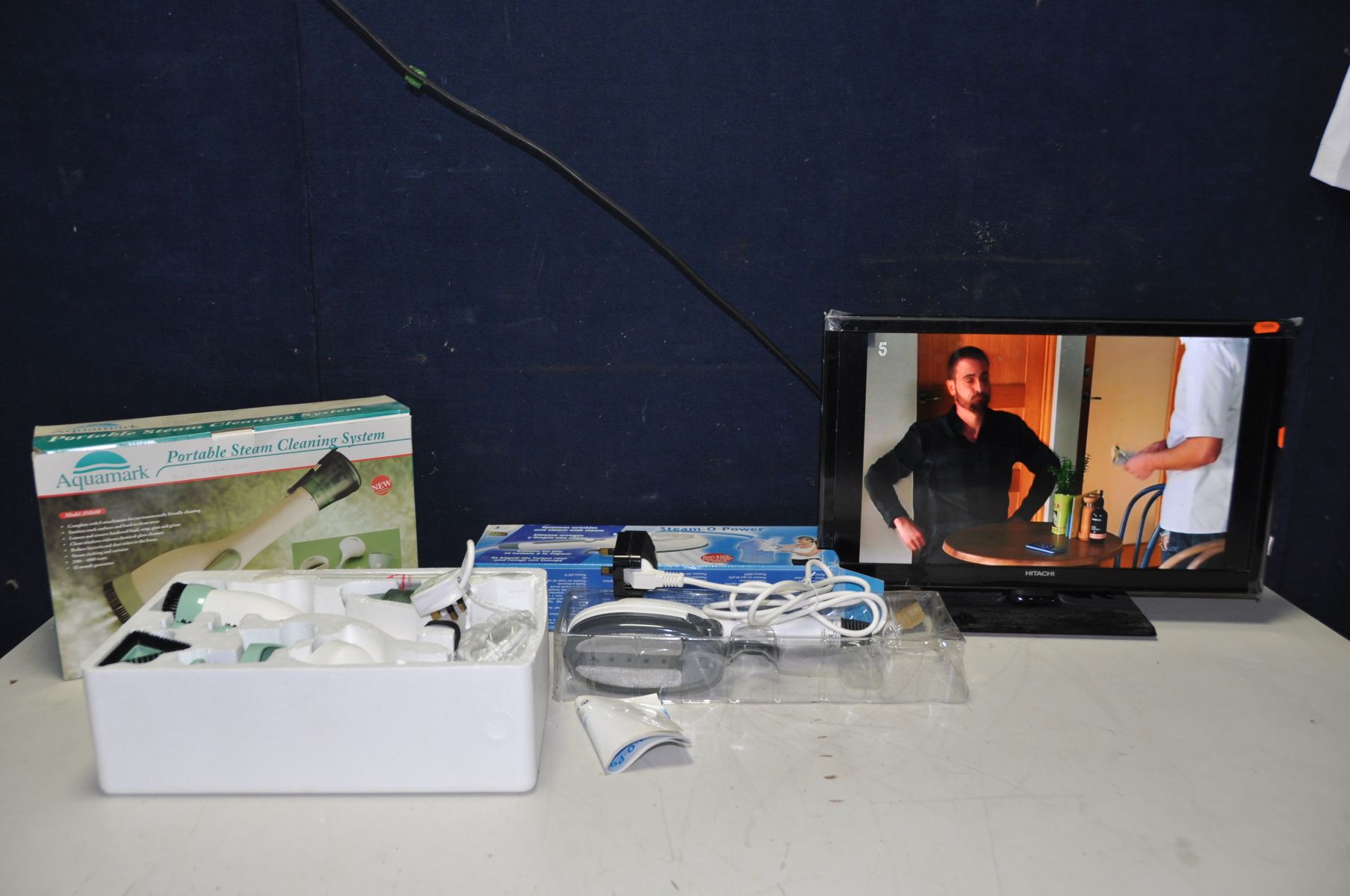 A HITATCHI 22HB11T06U 22in TV (no remote), Aquamark portable steam cleaning system in box and a
