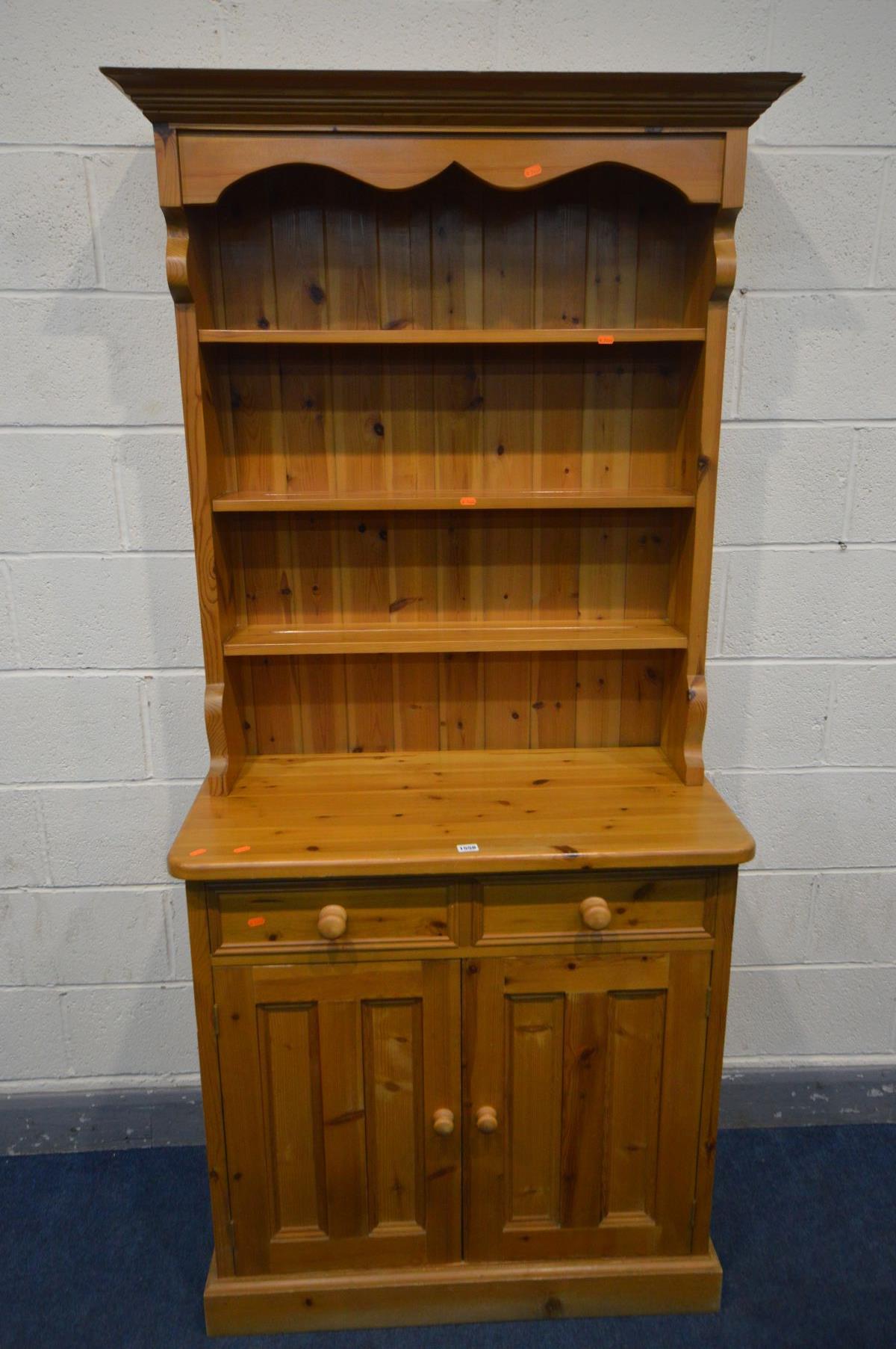 A SLIM PINE DRESSER, the top with triple plate rack, over a base with two drawer and double cupboard