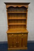 A SLIM PINE DRESSER, the top with triple plate rack, over a base with two drawer and double cupboard