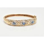 A 9CT GOLD SAPPHIRE AND DIAMOND HINGED BANGLE, set with three oval cut blue sapphires each within