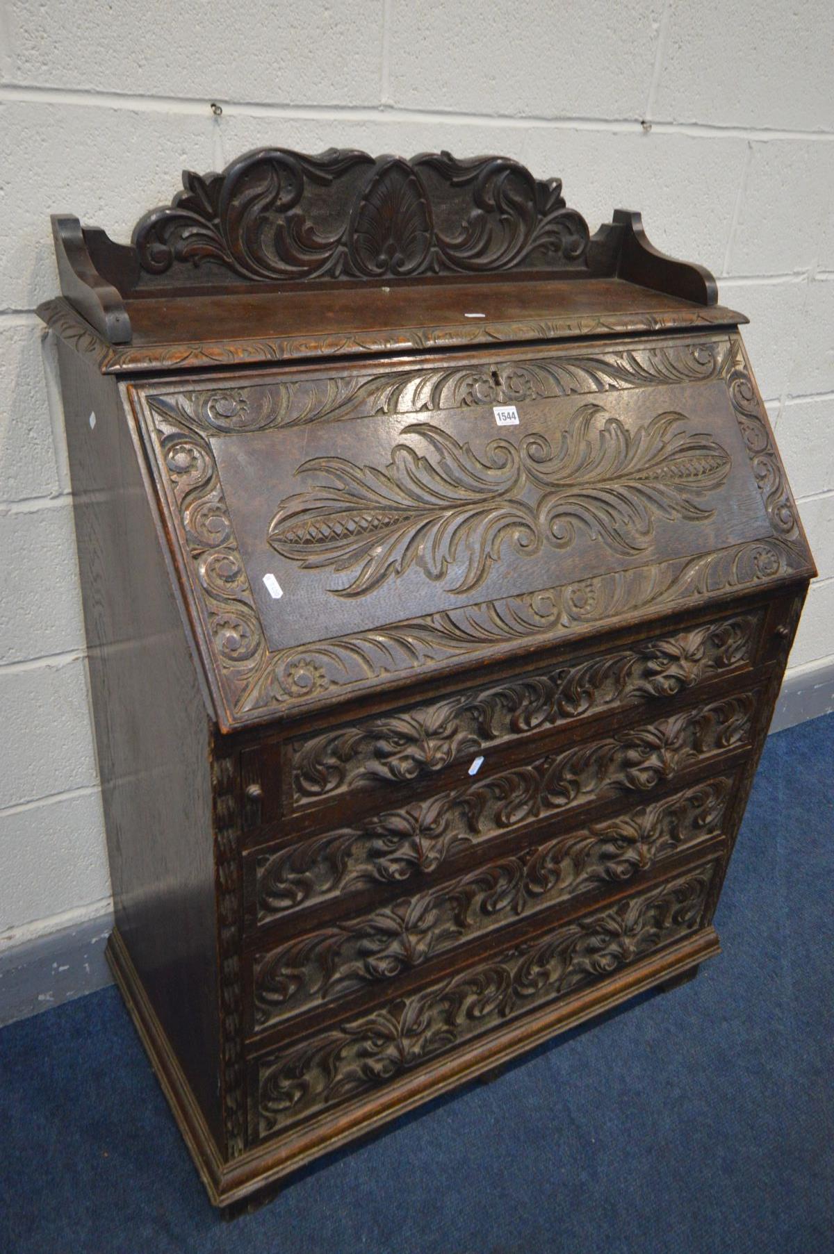 AN EARLY 20TH CENTURY CARVED OAK BUREAU, gallery top, the fall front with a fitted interior, above