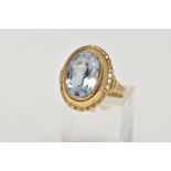 A YELLOW METAL BLUE TOPAZ DRESS RING, of an oval design, set with an oval cut light blue topaz (very