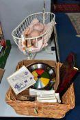 A METAL DOLLS CRADLE CONTAINING AN ARMAND MARSEILLE DOLL WITH A BASKET OF VINTAGE GAMES, to