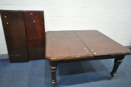 A LATE VICTORIAN MAHOGANY WIND OUT DINING TABLE, on turned fluted legs, brass caps and ceramic