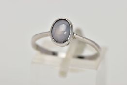 A STAR SAPPHIRE RING, the oval sapphire cabochon showing a six ray star, in a collet setting to